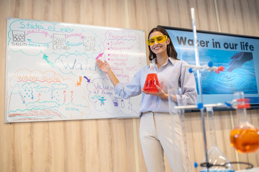 woman with flask near whiteboard looking camera Inspiring Excellence 2024